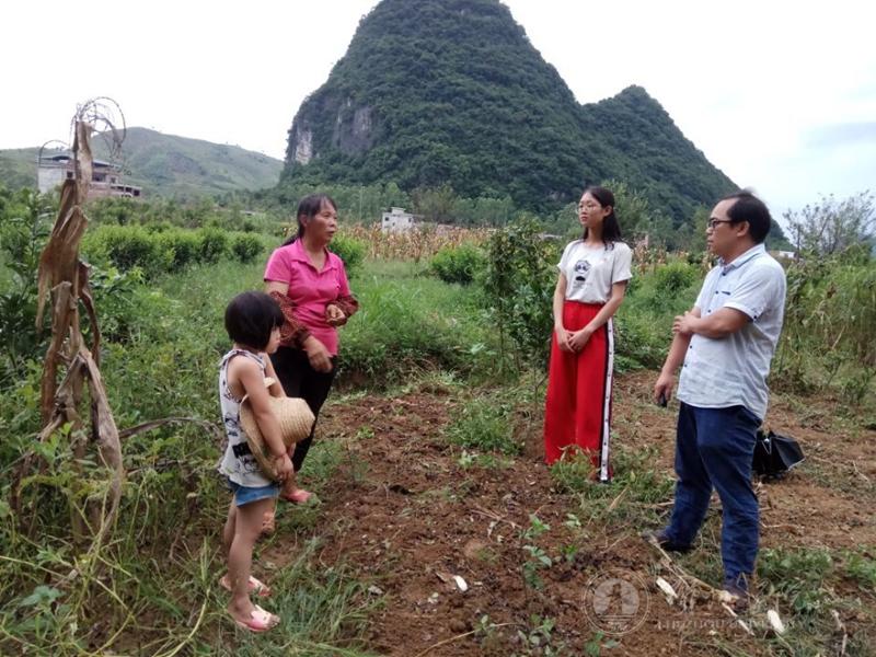 图为叶羽档在田间询问贫困户农业生产情况